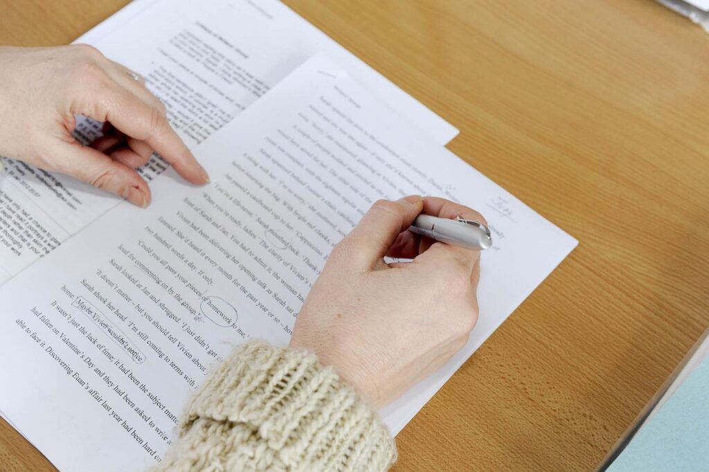 Person marking up a printed manuscript with a pen
