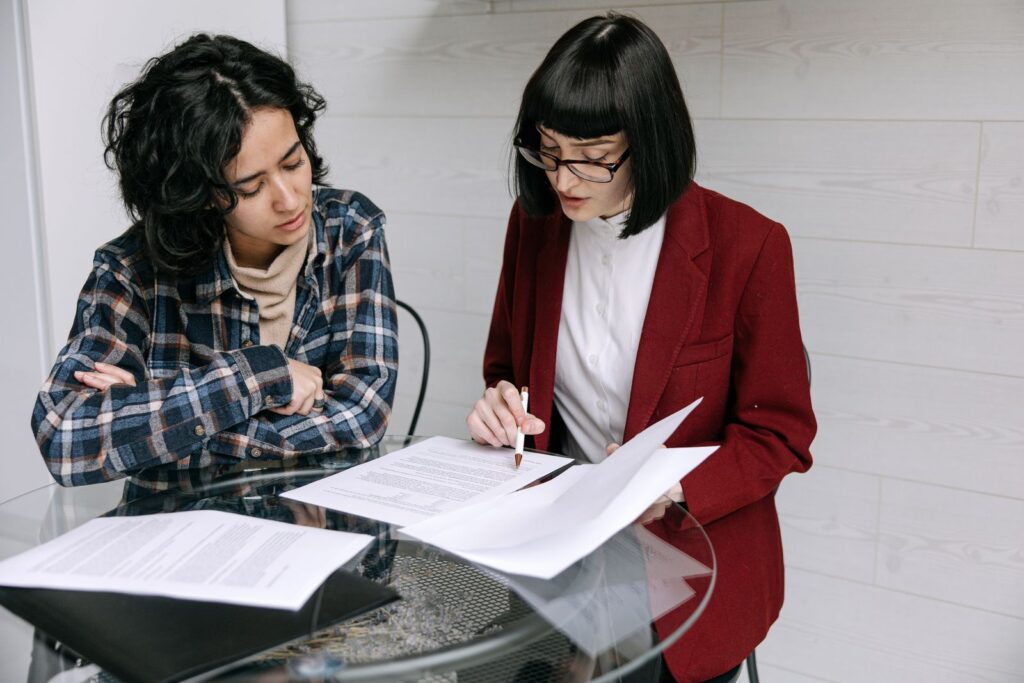 Two women reviewing printed documents together at a small table